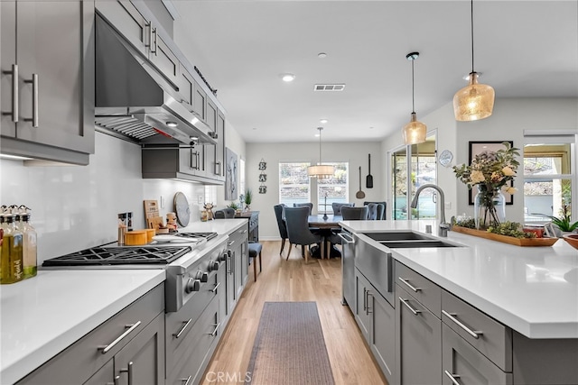 2760 Chad Zeller Ln, Corona, CA 92882 - kitchen featuring gray cabinetry, a sink, light wood-style floors, stainless steel gas cooktop, and light countertops