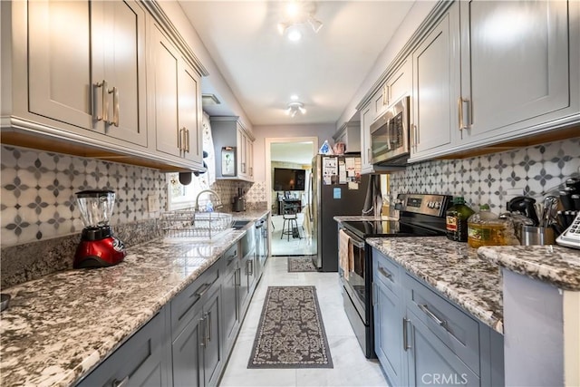 727 W Hill St, Long Beach, CA 90806 - kitchen featuring stainless steel appliances, gray cabinetry, decorative backsplash, and light stone countertops