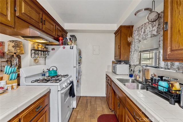 7614 Mason Ave, Winnetka, CA 91306 - kitchen with white gas stove, stainless steel microwave, tile counters, brown cabinetry, and light wood-style flooring
