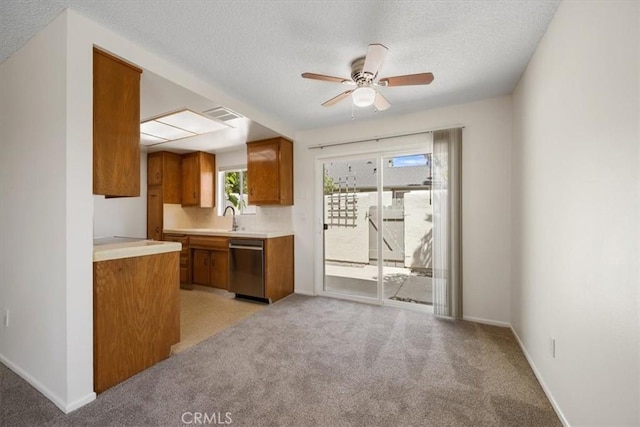 1750 Prefumo Canyon Rd Unit 17, San Luis Obispo, CA 93405 - kitchen with stainless steel dishwasher, brown cabinetry, light countertops, a ceiling fan, and a textured ceiling