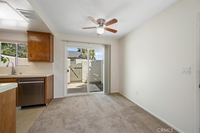 1750 Prefumo Canyon Rd Unit 17, San Luis Obispo, CA 93405 - kitchen with stainless steel dishwasher, brown cabinets, ceiling fan, light carpet, and tile countertops