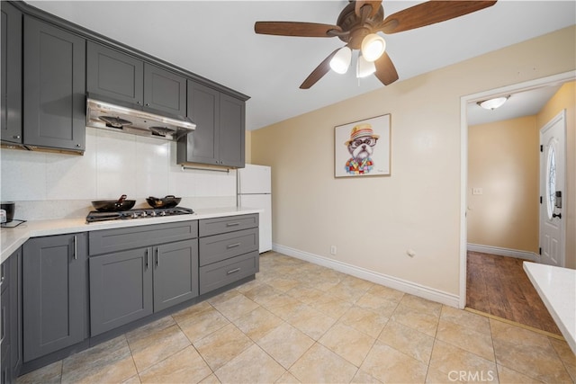 23929 Sunset Crossing Rd, Diamond Bar, CA 91765 - kitchen with under cabinet range hood, freestanding refrigerator, stainless steel gas cooktop, light countertops, and ceiling fan