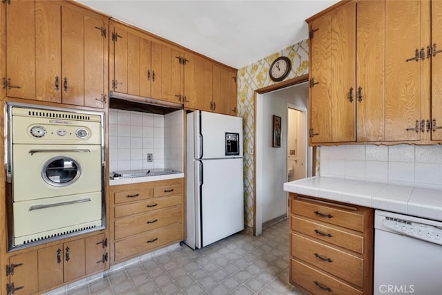 6130 Longridge Ave, Valley Glen, CA 91401 - kitchen with white appliances, under cabinet range hood, tasteful backsplash, wallpapered walls, and brown cabinets