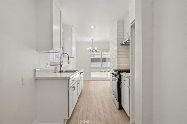 1304 N Devonshire Rd, Anaheim, CA 92801 - kitchen with stainless steel range with gas cooktop, a sink, light countertops, white cabinetry, and under cabinet range hood