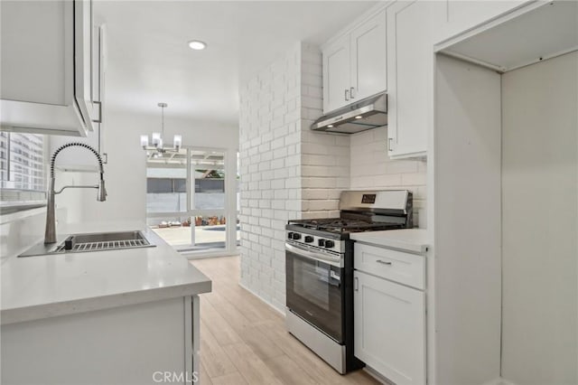 1304 N Devonshire Rd, Anaheim, CA 92801 - kitchen with gas stove, under cabinet range hood, a sink, light wood-type flooring, and a chandelier