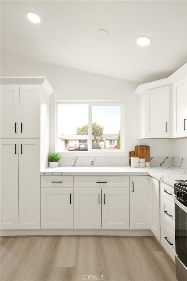 414 Markton St, Los Angeles, CA 90061 - kitchen with light wood-style floors, white cabinetry, stainless steel electric range, light stone counters, and recessed lighting