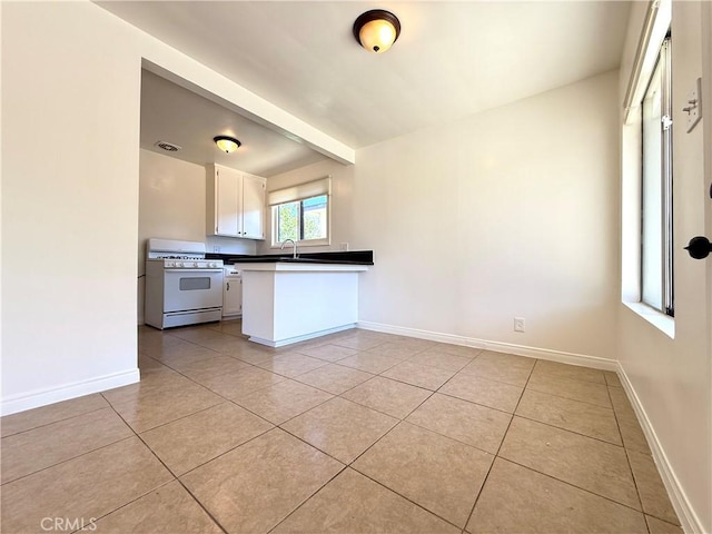 44037 Fern Ave, Lancaster, CA 93534 - kitchen featuring white gas range, a sink, a peninsula, light tile patterned floors, and white cabinetry