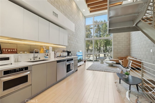 3450 Cahuenga Blvd W Unit 905, Los Angeles, CA 90068 - kitchen with a sink, stainless steel appliances, a towering ceiling, a wall of windows, and light countertops