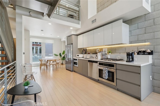 3450 Cahuenga Blvd W Unit 905, Los Angeles, CA 90068 - kitchen with stainless steel appliances, gray cabinetry, light countertops, light wood-style flooring, and a towering ceiling