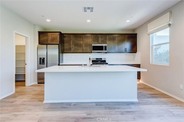 13139 Upland Ct, Hesperia, CA 92344 - kitchen with stainless steel appliances, dark brown cabinets, a kitchen island with sink, light countertops, and recessed lighting