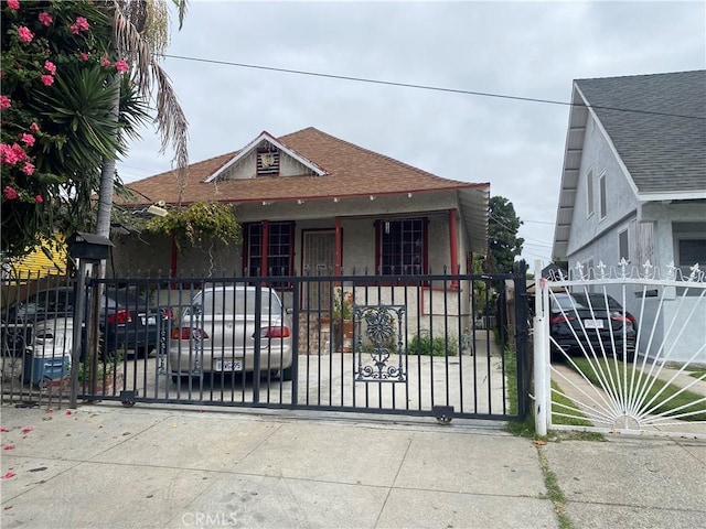 317 E 42nd Pl, Los Angeles, CA 90011 - bungalow-style house featuring a gate, a shingled roof, stucco siding, and covered porch