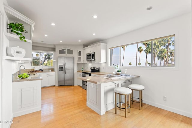 7560 Hollywood Blvd Unit 409, Los Angeles, CA 90046 - kitchen with appliances with stainless steel finishes, open shelves, a peninsula, a sink, and white cabinetry