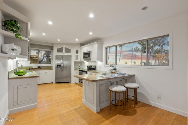 7560 Hollywood Blvd Unit 409, Los Angeles, CA 90046 - kitchen with appliances with stainless steel finishes, a peninsula, a sink, open shelves, and white cabinetry