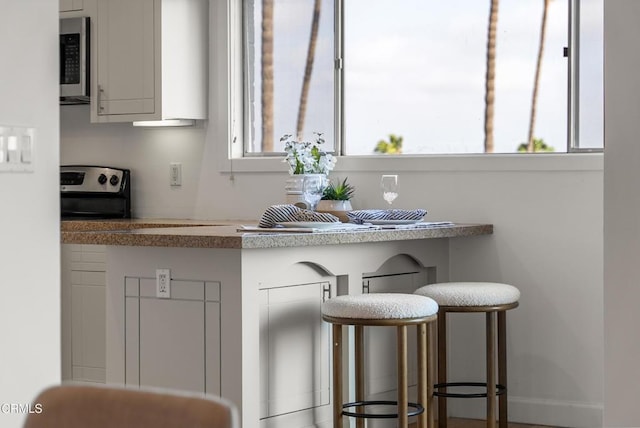 7560 Hollywood Blvd Unit 409, Los Angeles, CA 90046 - kitchen with stainless steel appliances, a kitchen breakfast bar, and white cabinets