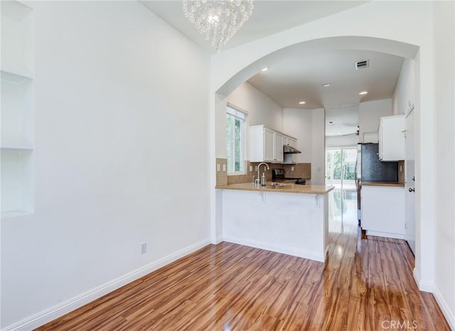 11259 Corsica Ct, Rancho Cucamonga, CA 91730 - kitchen with light wood finished floors, arched walkways, a peninsula, backsplash, and white cabinetry