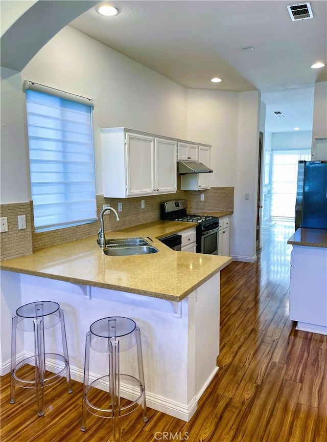 11259 Corsica Ct, Rancho Cucamonga, CA 91730 - kitchen with stainless steel gas stove, under cabinet range hood, fridge, a peninsula, and white cabinetry