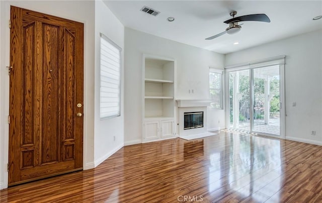 11259 Corsica Ct, Rancho Cucamonga, CA 91730 - unfurnished living room with built in shelves, a ceiling fan, wood finished floors, a glass covered fireplace, and recessed lighting