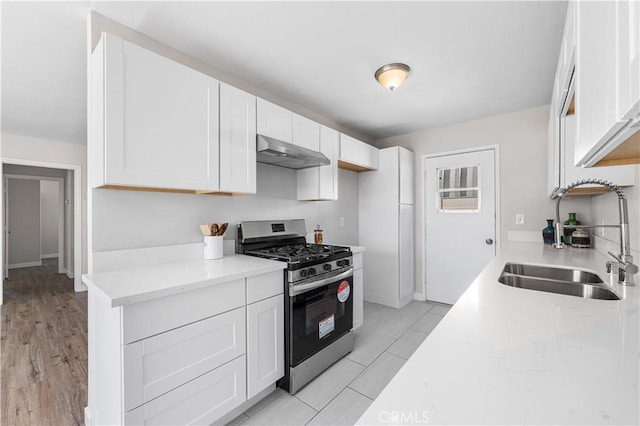 38881 Sage Tree St, Palmdale, CA 93551 - kitchen with stainless steel gas range, under cabinet range hood, a sink, and white cabinetry