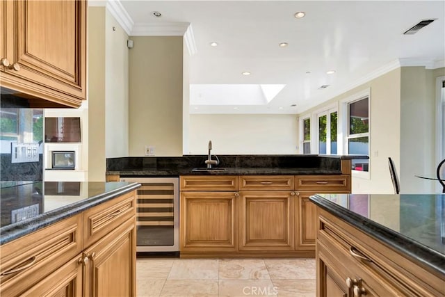5250 Calatrana Dr, Woodland Hills, CA 91364 - kitchen with wine cooler, crown molding, dark stone counters, recessed lighting, and brown cabinets