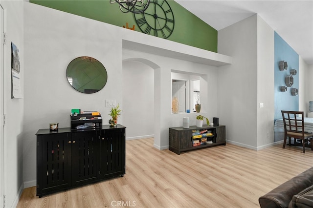 13797 Mesquite Dr, Fontana, CA 92337 - living room featuring wood finished floors, arched walkways, a towering ceiling, and baseboards