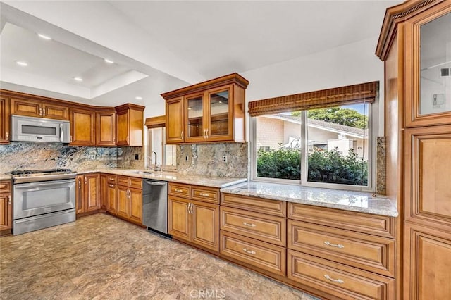 8815 Yuba Cir Unit 1102A, Huntington Beach, CA 92646 - kitchen with appliances with stainless steel finishes, a sink, brown cabinets, backsplash, and light stone counters