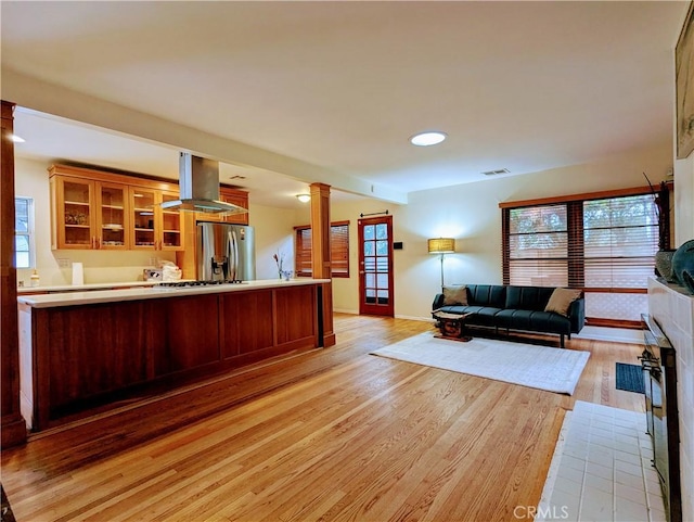 15123 Killion St, Sherman Oaks, CA 91411 - kitchen with stainless steel fridge, island exhaust hood, decorative columns, open floor plan, and light wood-type flooring