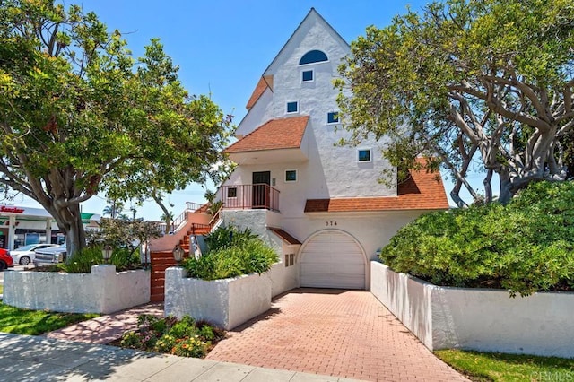 374 Orange Ave Unit F, Coronado, CA 92118 - view of front of home with stucco siding, a garage, stairs, and decorative driveway