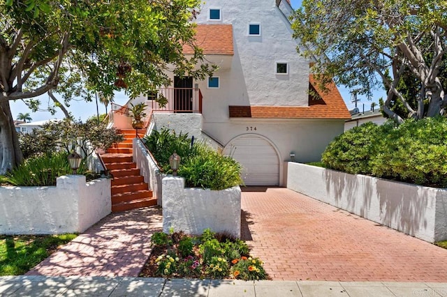 374 Orange Ave Unit F, Coronado, CA 92118 - view of front of home with stucco siding, decorative driveway, a garage, and stairway
