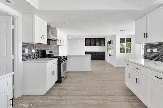 14855 Flathead Rd, Apple Valley, CA 92307 - kitchen with gas stove, wall chimney range hood, baseboards, white cabinetry, and decorative backsplash