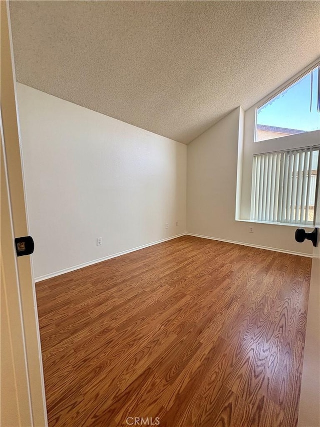 17081 Green Ln, Huntington Beach, CA 92649 - empty room featuring wood finished floors, vaulted ceiling, a textured ceiling, and baseboards