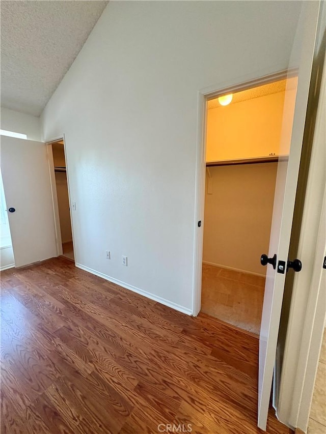 17081 Green Ln, Huntington Beach, CA 92649 - unfurnished bedroom with a textured ceiling, lofted ceiling, wood finished floors, and baseboards