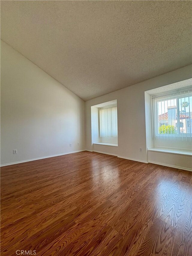 17081 Green Ln, Huntington Beach, CA 92649 - spare room with a textured ceiling, wood finished floors, vaulted ceiling, and baseboards