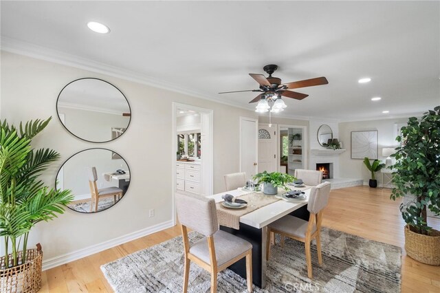 13782 Gershon Pl, North Tustin, CA 92705 - dining area featuring light wood finished floors, a ceiling fan, a warm lit fireplace, ornamental molding, and recessed lighting