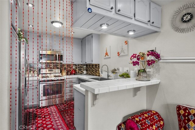 2346 Royal Ave Unit 9, Simi Valley, CA 93065 - kitchen with stainless steel appliances, a sink, a peninsula, tasteful backsplash, and a kitchen breakfast bar