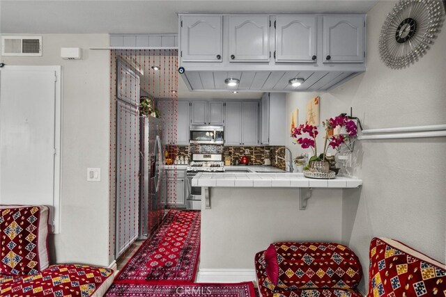 2346 Royal Ave Unit 9, Simi Valley, CA 93065 - kitchen with appliances with stainless steel finishes, tile counters, a peninsula, decorative backsplash, and a sink