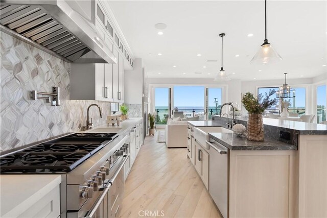 2141 Circle Dr, Hermosa Beach, CA 90254 - kitchen featuring stainless steel appliances, a sink, wall chimney exhaust hood, light wood-type flooring, and a kitchen island with sink