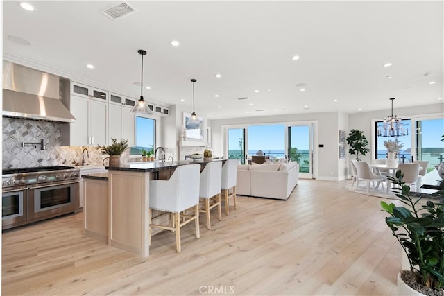 2141 Circle Dr, Hermosa Beach, CA 90254 - kitchen featuring range with two ovens, wall chimney range hood, backsplash, recessed lighting, and open floor plan