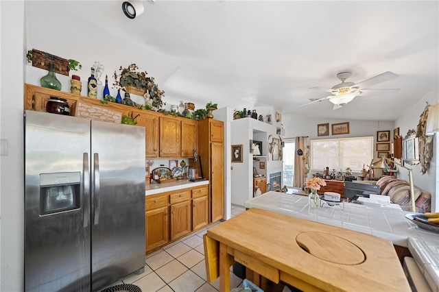32725 Trailwood Ct, Wildomar, CA 92595 - kitchen with stainless steel fridge with ice dispenser, tile countertops, ceiling fan, brown cabinetry, and vaulted ceiling