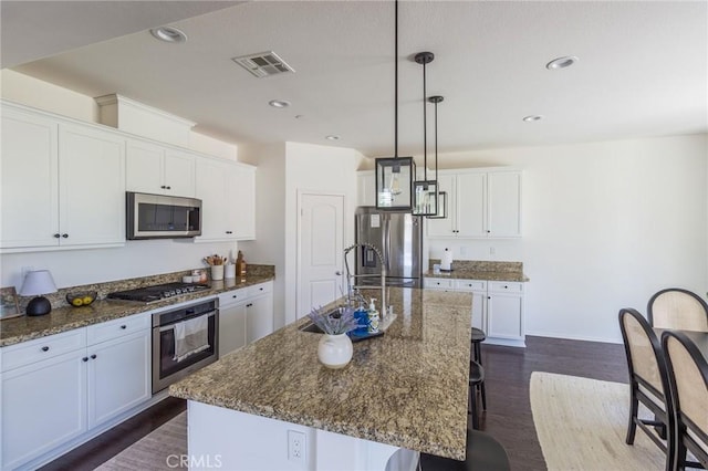 29590 Rawlings Way, Lake Elsinore, CA 92530 - kitchen featuring appliances with stainless steel finishes, a sink, a breakfast bar area, a center island with sink, and dark stone countertops
