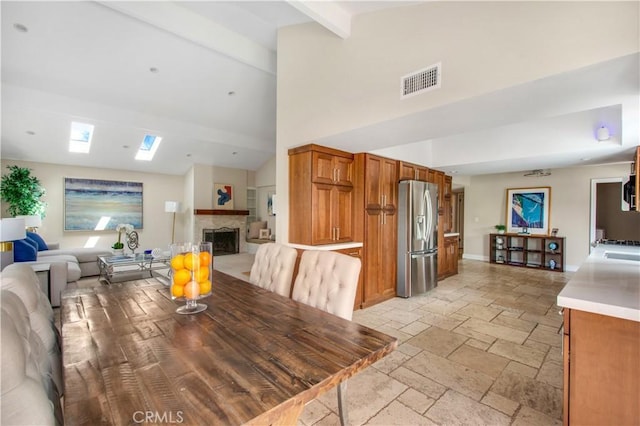 2662 Salmon Dr, Los Alamitos, CA 90720 - dining area featuring stone tile flooring, high vaulted ceiling, beam ceiling, a fireplace, and baseboards