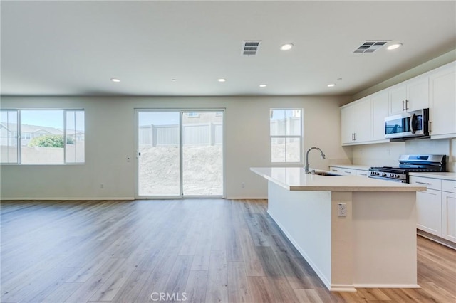 13119 Lancaster St, Hesperia, CA 92344 - kitchen featuring stainless steel appliances, a sink, a center island with sink, light countertops, and light wood-style flooring