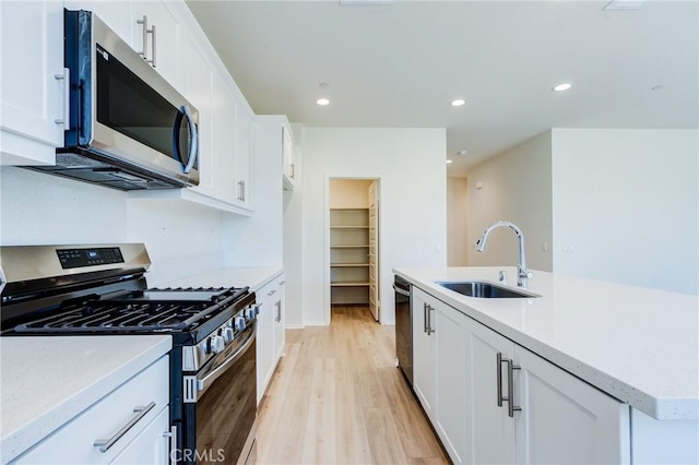 13119 Lancaster St, Hesperia, CA 92344 - kitchen featuring appliances with stainless steel finishes, a sink, light wood-style flooring, white cabinets, and light countertops