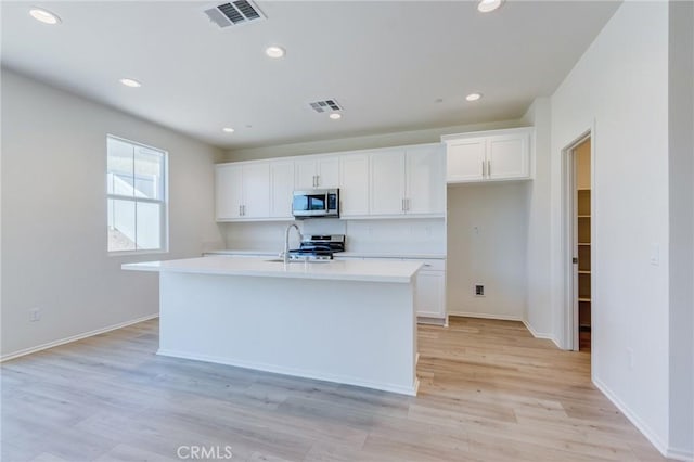 13119 Lancaster St, Hesperia, CA 92344 - kitchen featuring appliances with stainless steel finishes, white cabinets, light countertops, recessed lighting, and an island with sink