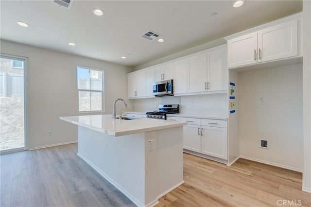 13119 Lancaster St, Hesperia, CA 92344 - kitchen featuring appliances with stainless steel finishes, a sink, an island with sink, light wood-style flooring, and white cabinetry