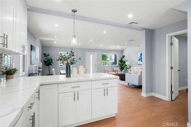 1223 W 90th St, Los Angeles, CA 90044 - kitchen with a peninsula, white cabinets, light stone countertops, light wood-type flooring, and recessed lighting