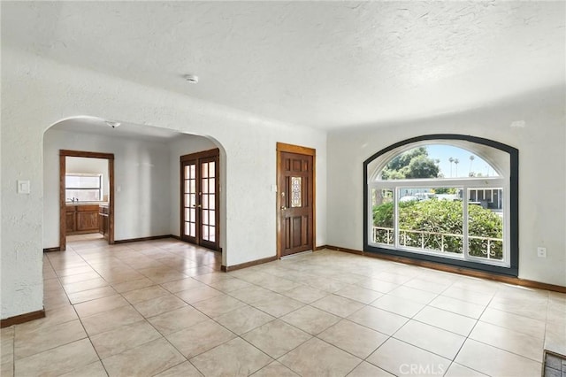 541 Randolph St, Pomona, CA 91768 - spare room featuring arched walkways, a textured ceiling, light tile patterned floors, and a textured wall