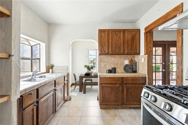 541 Randolph St, Pomona, CA 91768 - kitchen with tile countertops, light tile patterned floors, stainless steel gas stove, french doors, and tasteful backsplash