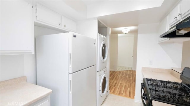 14610 Erwin St, Van Nuys, CA 91411 - kitchen featuring stacked washer / drying machine, black range with gas stovetop, freestanding refrigerator, light countertops, and white cabinets