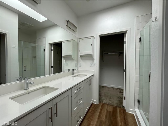 2318 Synergy, Irvine, CA 92614 - full bathroom with a shower stall, wood finished floors, double vanity, a walk in closet, and a skylight
