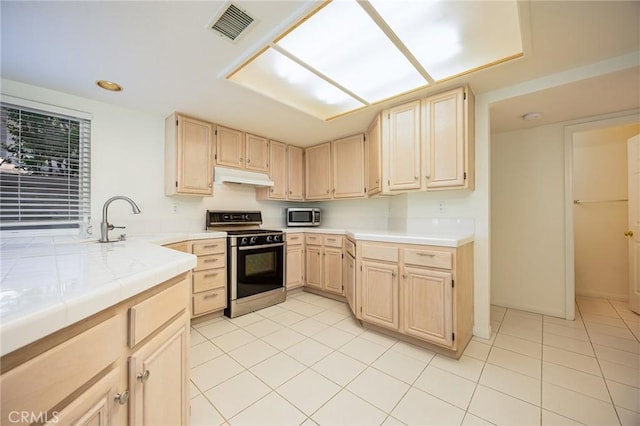 24177 Morning Dove Ln, Murrieta, CA 92562 - kitchen with gas range oven, light brown cabinets, under cabinet range hood, stainless steel microwave, and recessed lighting